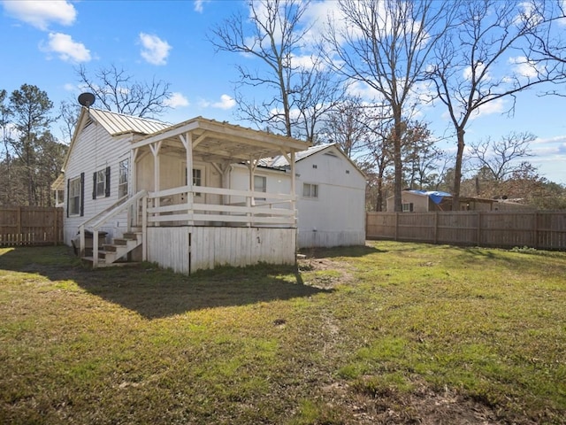 rear view of property with metal roof, a lawn, and fence