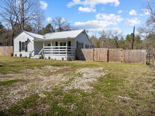 view of front facade featuring a porch, a front yard, a gate, metal roof, and fence