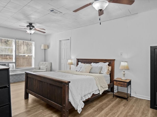 bedroom featuring baseboards, visible vents, ceiling fan, and wood finished floors