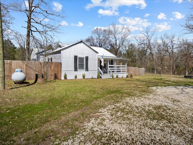 view of front of home with covered porch, fence, and a front lawn