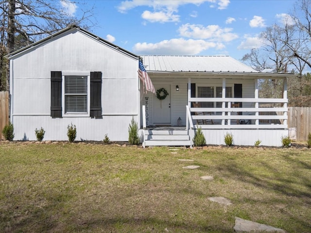 view of front facade with a porch, metal roof, a front lawn, and fence