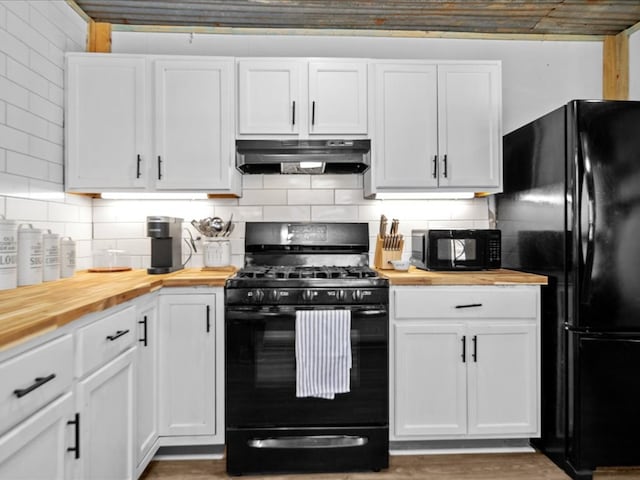 kitchen with black appliances, wood counters, under cabinet range hood, and white cabinets