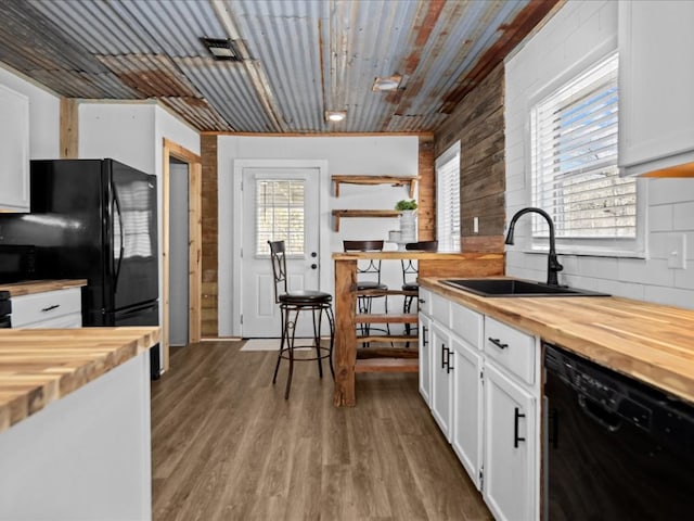 kitchen featuring a sink, wood counters, black appliances, and wood finished floors