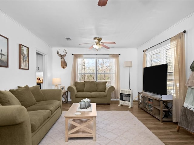 living room featuring heating unit, a healthy amount of sunlight, and wood finished floors