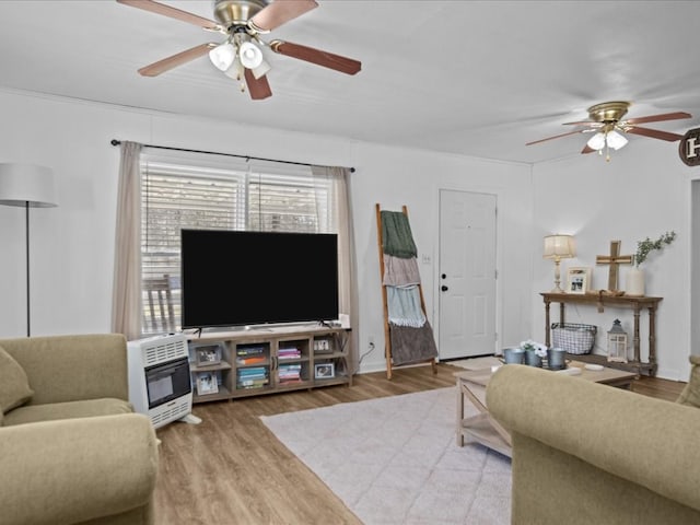 living area with a ceiling fan, heating unit, and wood finished floors