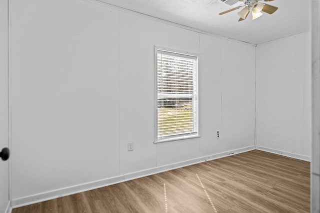 empty room featuring wood finished floors, a ceiling fan, and baseboards