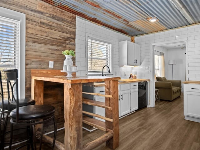 kitchen with black dishwasher, butcher block countertops, dark wood-type flooring, and white cabinetry