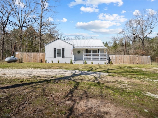 view of front facade with covered porch, fence, metal roof, and a front yard