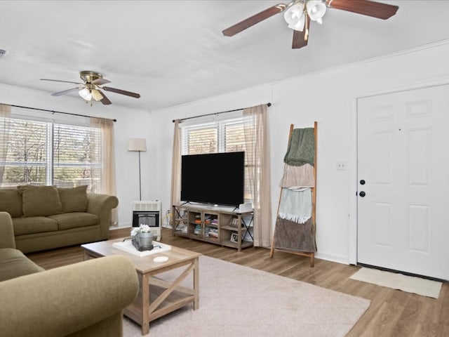 living room featuring ceiling fan, wood finished floors, visible vents, baseboards, and heating unit