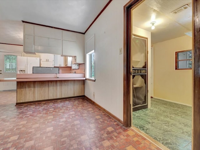 602 Devereaux, Diboll, TX 75941 - kitchen featuring white fridge with ice dispenser, a peninsula, white cabinets, light countertops, and crown molding