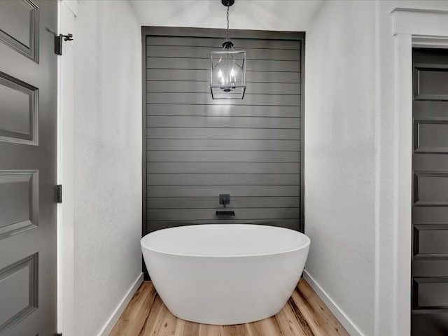 1920 Fm 842, Lufkin, TX 75901 - bathroom featuring wood finished floors, a soaking tub, and a chandelier