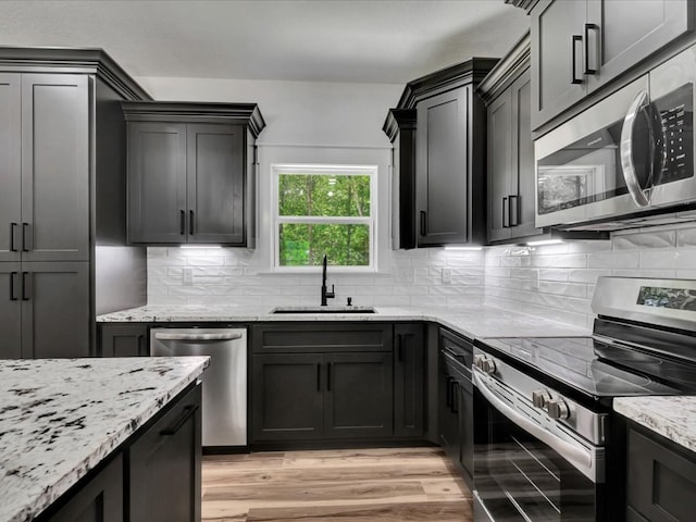 1920 Fm 842, Lufkin, TX 75901 - kitchen featuring appliances with stainless steel finishes, light stone counters, decorative backsplash, and light wood-style floors
