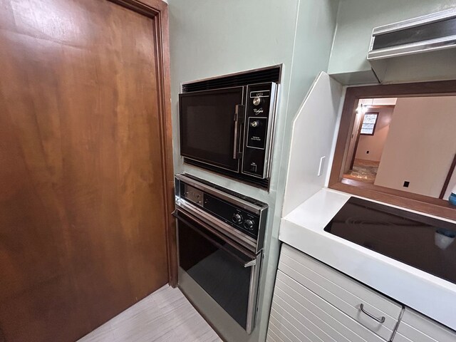 kitchen featuring black microwave, light countertops, and wall oven