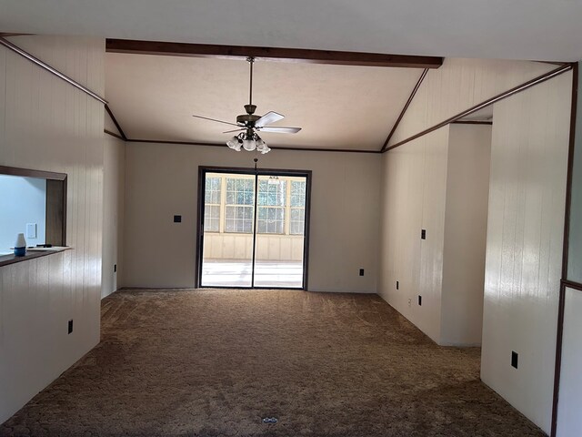 carpeted spare room featuring lofted ceiling with beams, wood walls, and a ceiling fan