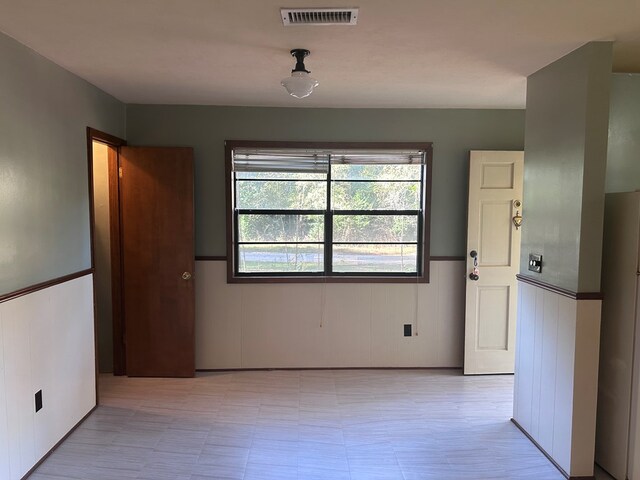 unfurnished dining area with a wainscoted wall and visible vents