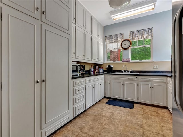 107 W Kerr Ave, Lufkin, TX 74904 - kitchen featuring refrigerator, dark countertops, and white cabinetry