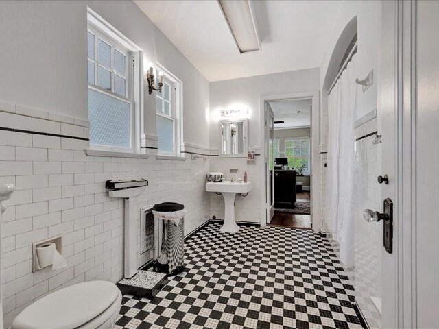 107 W Kerr Ave, Lufkin, TX 74904 - full bathroom featuring tile walls, wainscoting, tile patterned floors, and a shower with shower curtain