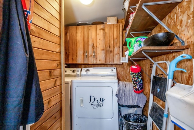clothes washing area featuring wooden walls, laundry area, and independent washer and dryer