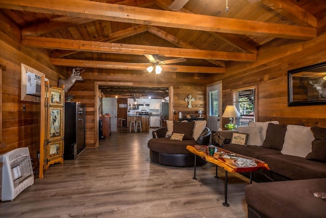 living area with heating unit, vaulted ceiling with beams, wooden walls, and ceiling fan