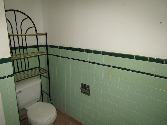 bathroom featuring toilet and tile walls