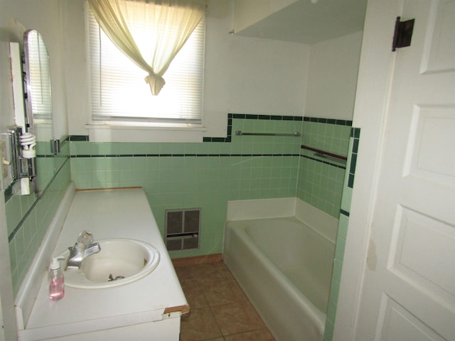 bathroom with tile patterned flooring, vanity, a tub to relax in, and tile walls