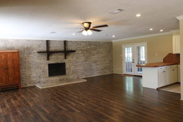 unfurnished living room featuring ceiling fan, crown molding, dark wood-type flooring, and french doors