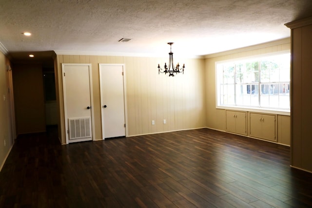 unfurnished room featuring a textured ceiling, dark hardwood / wood-style floors, an inviting chandelier, and crown molding