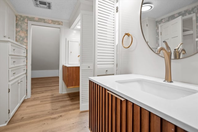 109 Innisbrook Dr, Lufkin, TX 75901 - bathroom featuring a textured ceiling, ornamental molding, wood finished floors, wallpapered walls, and vanity