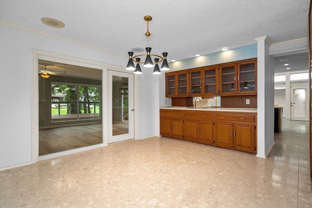 109 Innisbrook Dr, Lufkin, TX 75901 - kitchen featuring brown cabinets, light countertops, a chandelier, glass insert cabinets, and pendant lighting