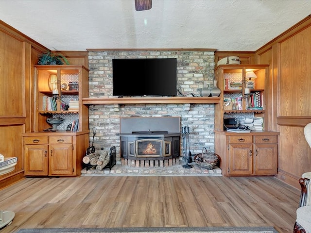 128 Tamie Lowe Rd, Moscow, TX 75960 - living room featuring crown molding, light wood-type flooring, a brick fireplace, a textured ceiling, and wooden walls