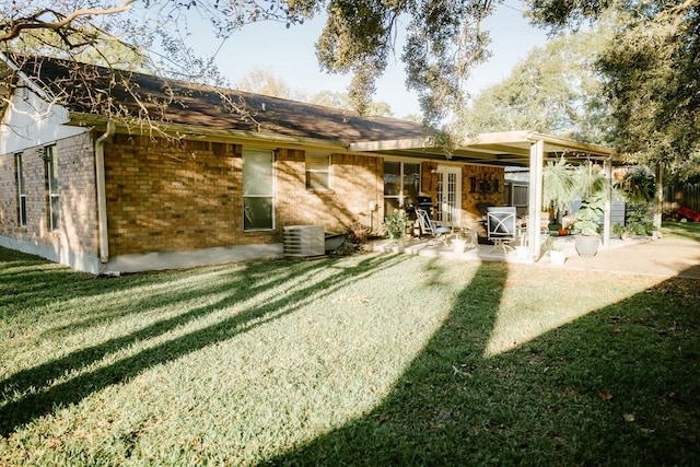 rear view of property with a yard, cooling unit, and a patio area