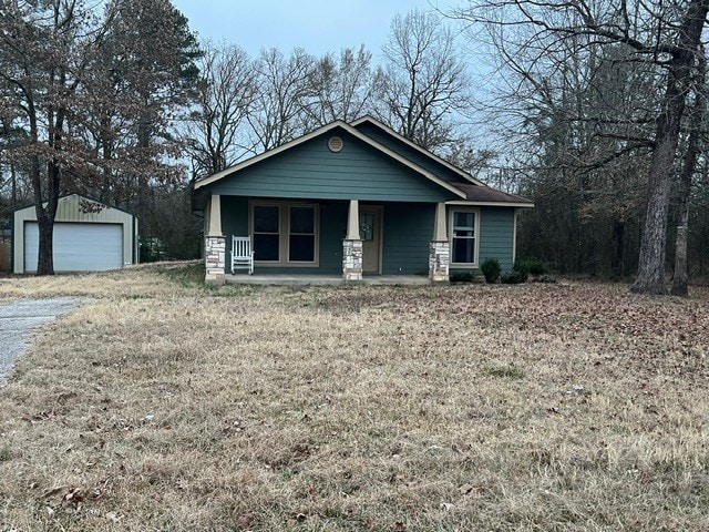 view of front of house featuring a garage, an outdoor structure, a front yard, and a porch