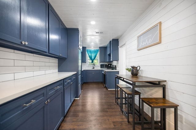 213 Lee Ln, Lufkin, TX 75904 - kitchen with blue cabinets, dark wood finished floors, backsplash, and wooden walls