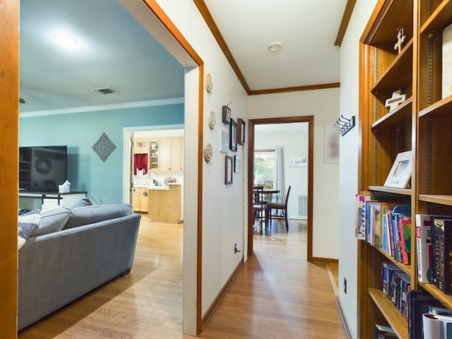 corridor with light hardwood / wood-style flooring and ornamental molding