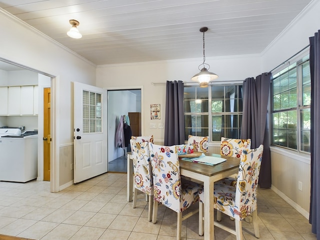 dining area with light tile patterned floors, washer / clothes dryer, crown molding, and wood walls