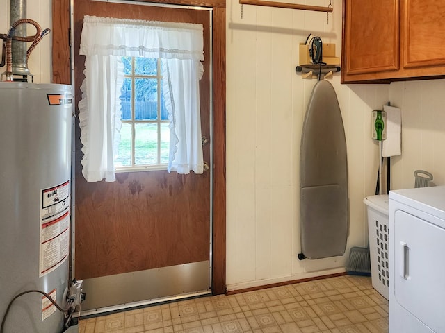 laundry area featuring light floors, washer / dryer, cabinet space, wood walls, and gas water heater