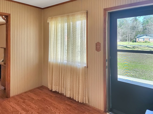 doorway to outside with wood finished floors and crown molding