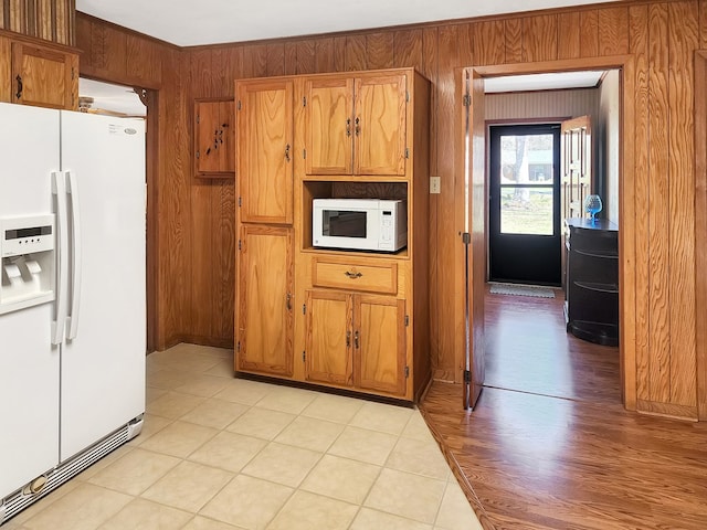 kitchen with white appliances, wood walls, and brown cabinetry