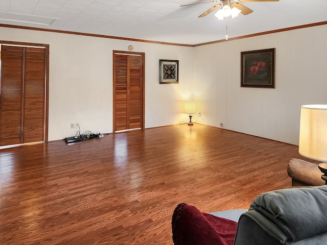 living area featuring crown molding, a ceiling fan, and wood finished floors