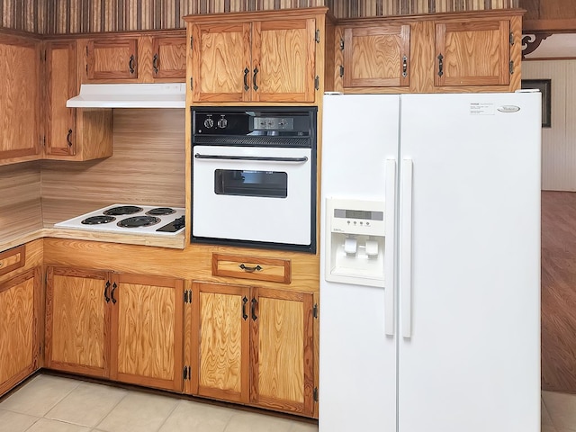 kitchen featuring white appliances, light countertops, brown cabinets, and under cabinet range hood