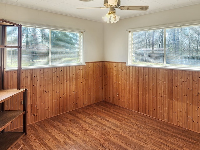 unfurnished room featuring ceiling fan, wood finished floors, wainscoting, and wood walls