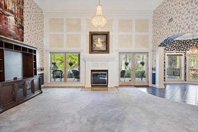 unfurnished living room with a high ceiling, crown molding, a chandelier, and carpet flooring