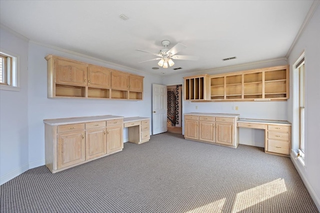 kitchen featuring crown molding, light brown cabinets, and built in desk