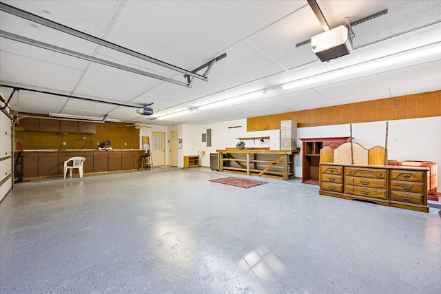 garage featuring electric panel, a workshop area, and a garage door opener