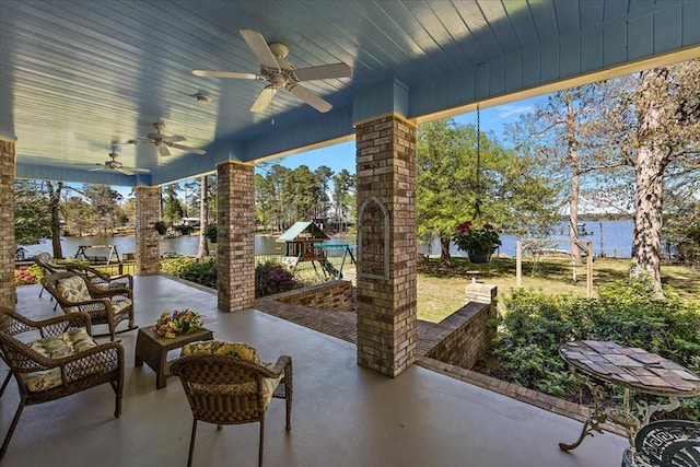 view of patio / terrace featuring ceiling fan, a playground, and a water view