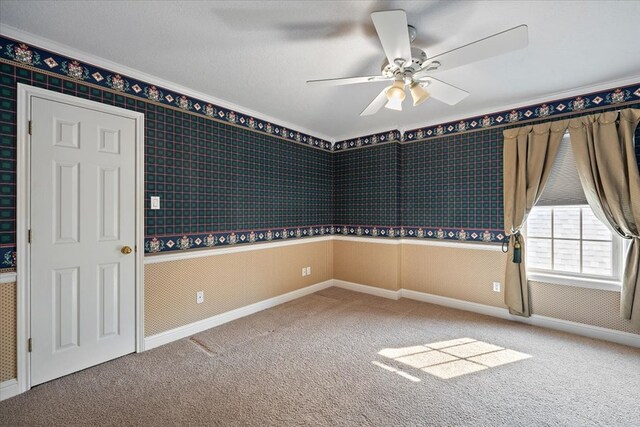 carpeted home office with ceiling fan, built in desk, wood walls, and a textured ceiling