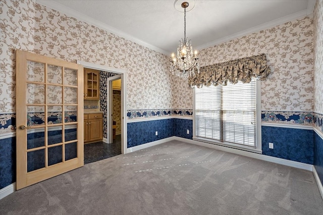 carpeted empty room featuring ornamental molding and an inviting chandelier