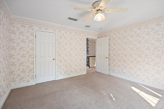 carpeted spare room featuring ceiling fan and crown molding