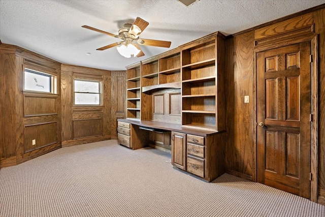 445 Riverbend Dr, Hemphill, TX 75948 - office area featuring a textured ceiling, wooden walls, built in desk, a ceiling fan, and light carpet