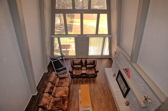 living room with hardwood / wood-style flooring, a brick fireplace, and a wealth of natural light